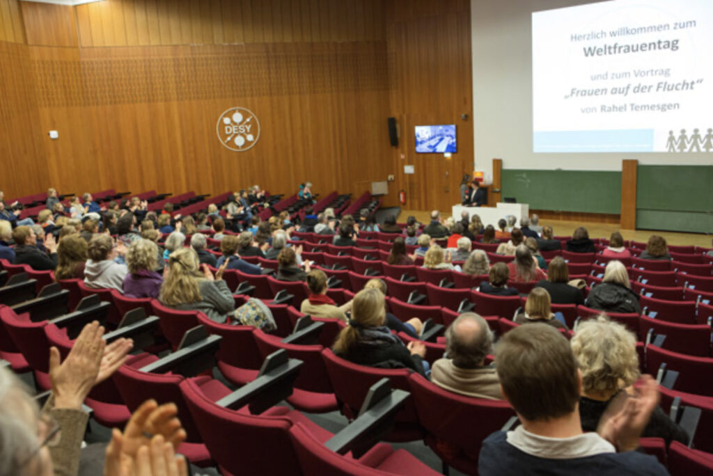 Eindrücke der Veranstaltung zum 8. März 2016 im Abaton Kino. Zu sehen sind Rednerinnen auf dem Podium und Gästinnen im Publikum.