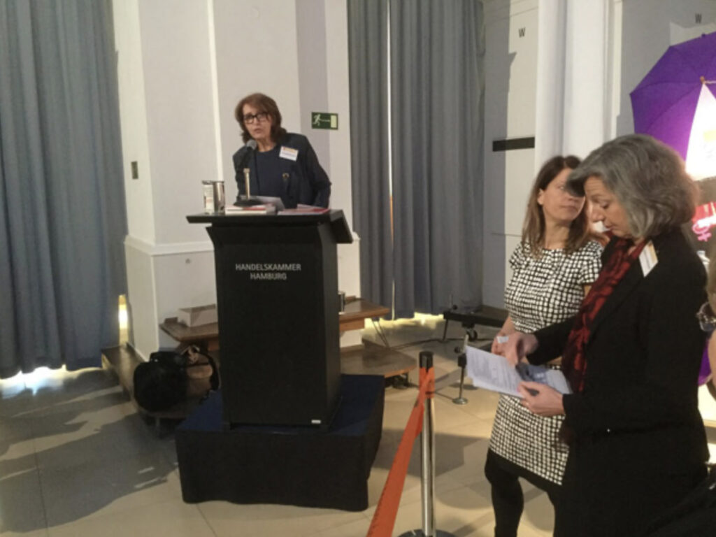 Eindrücke der Veranstaltung zum 8. März 2016 im Abaton Kino. Zu sehen sind Rednerinnen auf dem Podium und Gästinnen im Publikum.